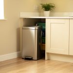 Cuisine familiale lumineuse et contemporaine avec une poubelle à pédale en inox près du plan de travail et des bacs de tri discrets.