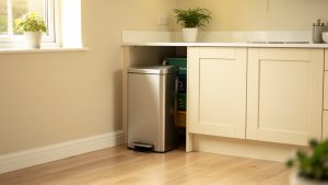 Cuisine familiale lumineuse et contemporaine avec une poubelle à pédale en inox près du plan de travail et des bacs de tri discrets.